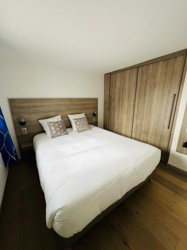 - un grand lit blanc dans une chambre dotée de murs en bois dans l'établissement Macareux - Laïta Guidel, à Guidel