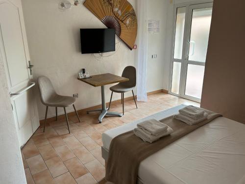 a bedroom with a bed and a table and chairs at Logis Hotel De La Clape in Narbonne-Plage