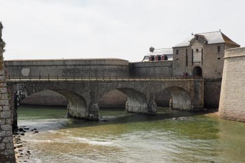 a stone bridge over a river with a building at Feet in the water breathtaking 180 sea view! in Port-Louis