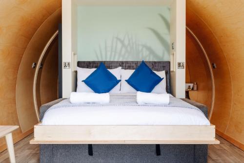 a bedroom with a bed with blue pillows at Loch Buie Pod in Pennyghael