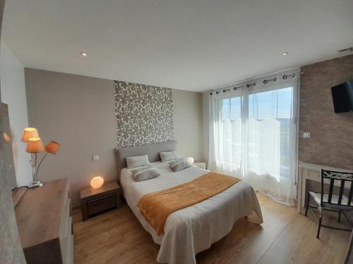 ein Schlafzimmer mit einem großen Bett und einem großen Fenster in der Unterkunft Chambre d'hôtes Les Bruyères in Bruc-sur-Aff