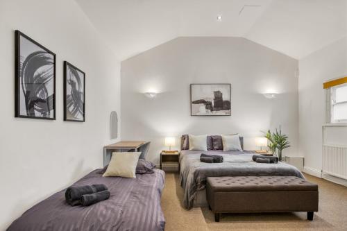a bedroom with two beds and a chair at Vibrant 2-Bed by Bow in London