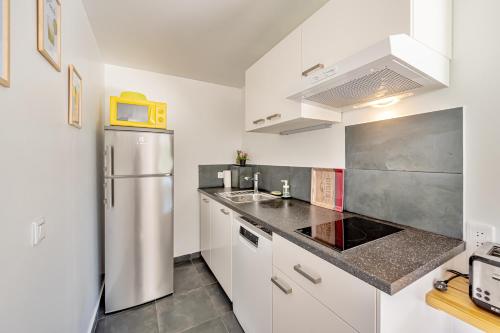 une cuisine avec des armoires blanches et un réfrigérateur en acier inoxydable dans l'établissement Grand T2 Clim & Wifi en Rez de villa proche mer, à Hyères