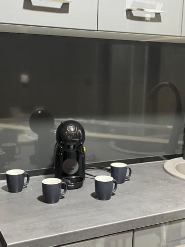 a coffee maker sitting on a counter with four coffee cups at Diamond Hostel in Divčibare