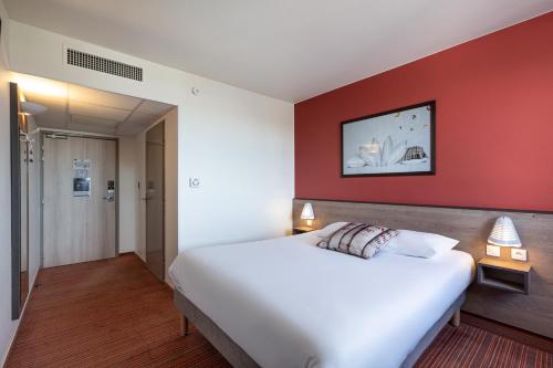ein Schlafzimmer mit einem weißen Bett und einer roten Wand in der Unterkunft Ace Hotel Roanne in Mably