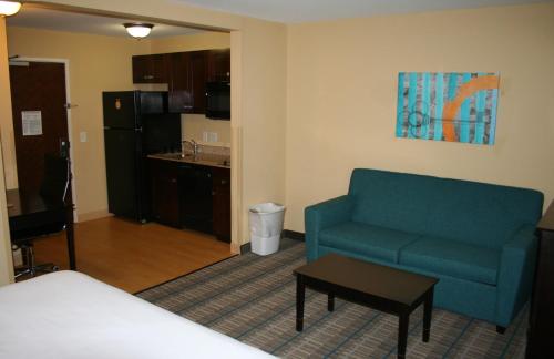 uma sala de estar com um sofá azul e uma cozinha em MainStay Suites Jacksonville near Camp Lejeune em Jacksonville