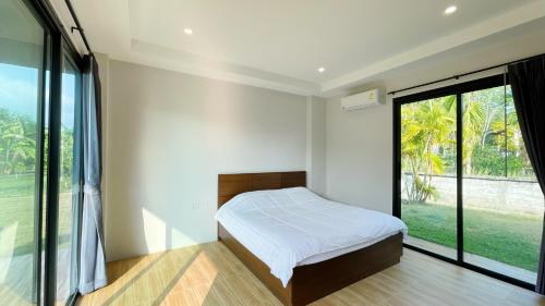 a bedroom with a bed and a large window at Spacious Private Villa Modern Style near beach in Thai Muang