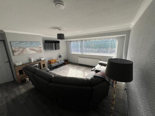 a living room with a couch and a large window at Dawson's Corner Retreat in Beadnell