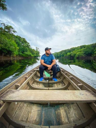 a man sitting in a wooden boat on a river at POUSADA DA DRI LODGE in Iranduba