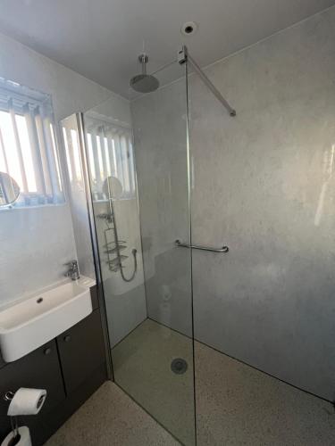 a bathroom with a glass shower and a sink at Dawson's Corner Retreat in Beadnell