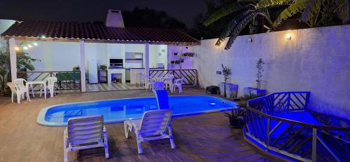 uma piscina azul com cadeiras e uma mesa em Pousada dos Félix em São Gabriel