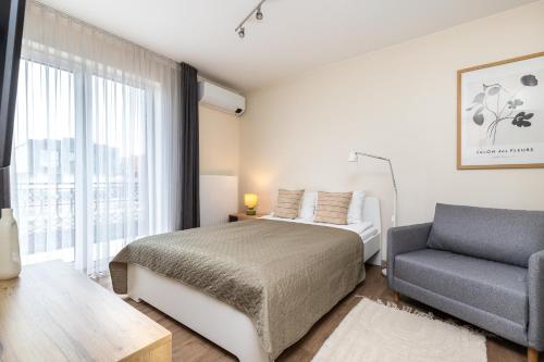 a bedroom with a bed and a chair and a window at Vila Sonata Palanga in Palanga