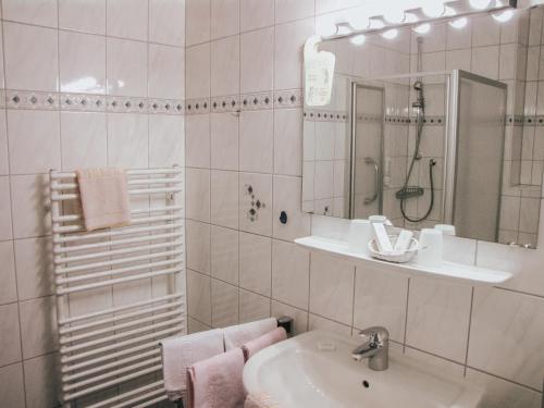 Hotel Harzer am Kurpark في باد هيرنالب: حمام أبيض مع حوض ومرآة