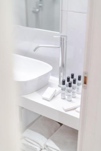 a white bathroom with a sink and a mirror at Athens Cypria Hotel in Athens