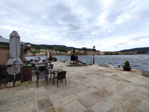 een patio met tafels en stoelen naast een waterlichaam bij Casa Freitas in Combarro