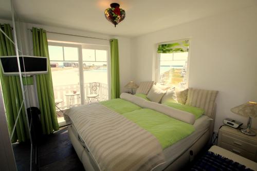 a bedroom with a green and white bed and a window at Strandhaus Libelle - direkt am Strand der Ostsee in Kappeln