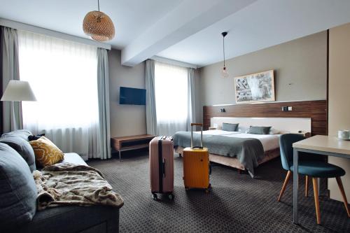 グダニスクにあるHotel Beethovenのベッドとスーツケース付きのホテルルーム