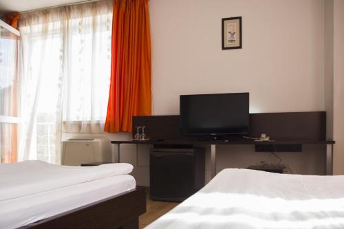 a hotel room with two beds and a flat screen tv at Villa Grande in Iaşi