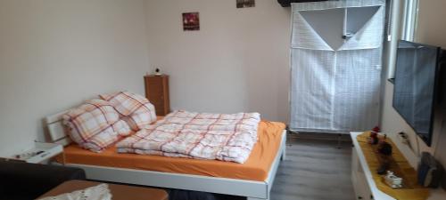 a bedroom with a bed with an orange blanket and a window at Ferienhaus Sonne in Nordhausen