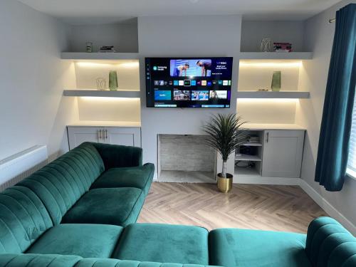 a living room with a green couch and a flat screen tv at Impeccable 3-Bed House in Walsall in Walsall