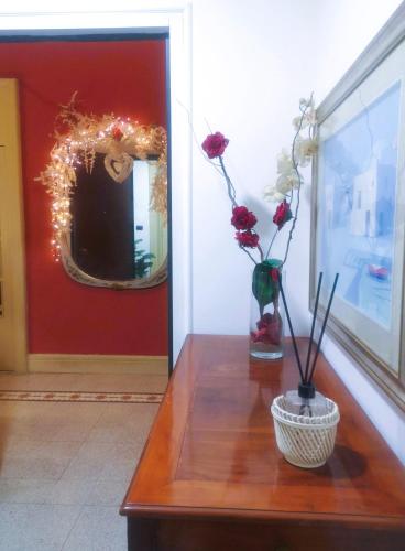 a table with a mirror and a vase with flowers on it at B&B PARNASO in Torre Annunziata