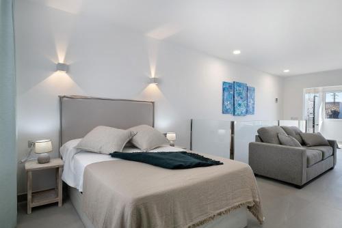 a white bedroom with a bed and a chair at Casa Mara 2 in Playa Quemada