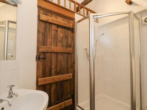 a bathroom with a wooden door and a sink and a shower at Bluebell in Woodbridge