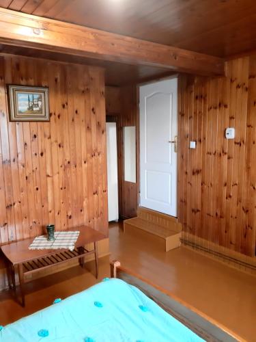 Pokój z drewnianymi ścianami, stołem i oknem w obiekcie Apartament na wsi w Lubniewicach