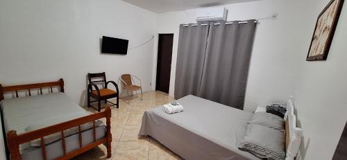 a bedroom with two beds and a television in it at Pousada Felix in São Gabriel