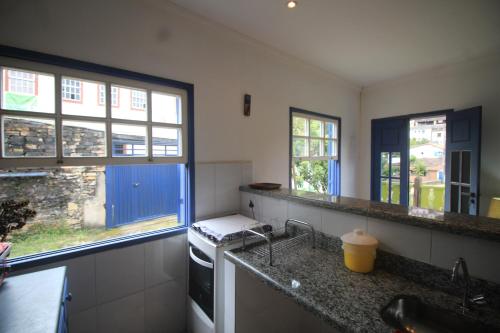 a kitchen with a sink and two windows at Casazul - OP in Ouro Preto