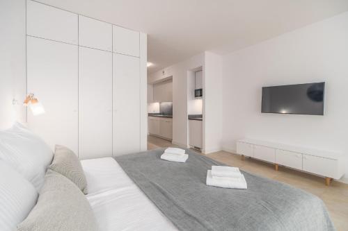 a white bedroom with a bed with two towels on it at Aquamarina Prima 07 Seaside Studio by the BEACH with Terrace by Renters in Międzyzdroje