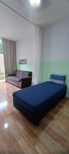 a bedroom with a blue bed and a couch at Apê Estúdio Tropical in Paranaíba