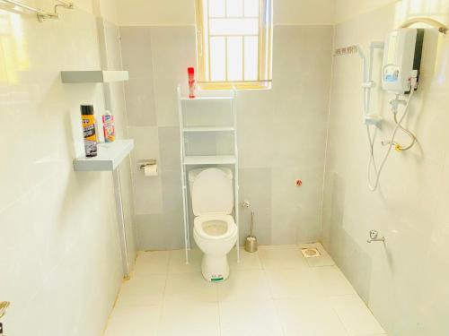 une petite salle de bains avec des toilettes et une étagère. dans l'établissement StarHomes, Jinja, à Jinja