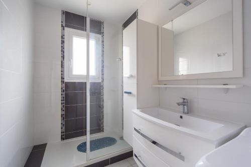 une salle de bain blanche avec un lavabo et une douche dans l'établissement Villa du Lac des Sablons, à Belleville-sur-Saône