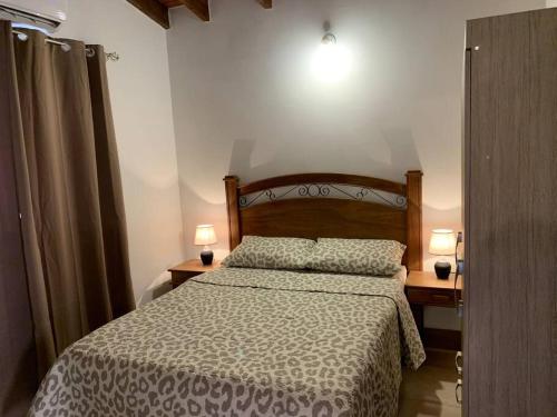 a bedroom with a bed and two lamps on two tables at Hermosa casa, zona Aeropuerto in Luque