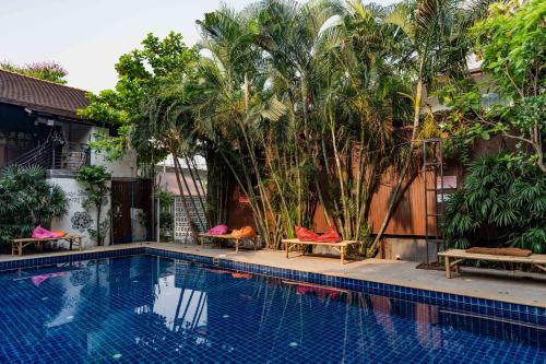 a swimming pool with chairs and palm trees next to a building at Mammoth Boutique Hotel in Chiang Mai