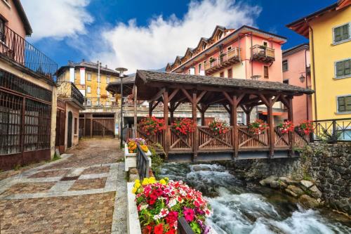 een brug over een rivier in een stad met bloemen bij Casa Dolce Presena in Passo del Tonale