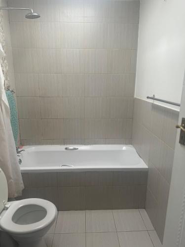 y baño con bañera blanca y aseo. en Affordable Guest house in Mwobray, en Ciudad del Cabo