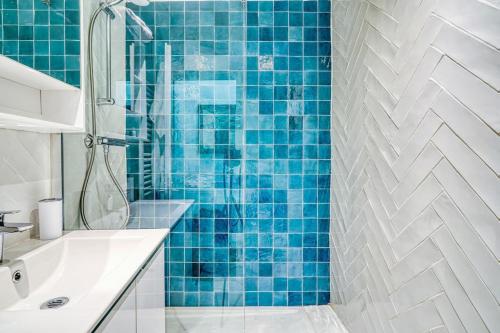 La salle de bains est pourvue de carrelage bleu, d'une douche et d'un lavabo. dans l'établissement Apartment 3 People Voltaire-Saint Ambroise, à Paris