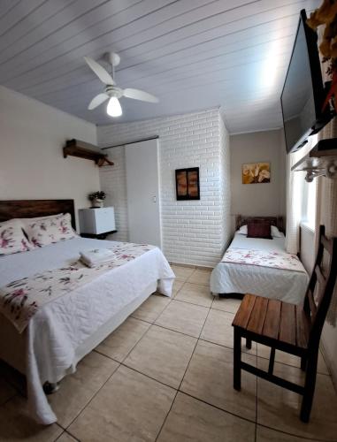 a bedroom with two beds and a ceiling fan at Pousada Vila Flor in Rio das Flores