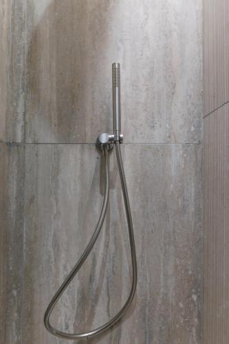 une douche avec un tuyau fixé à un mur dans l'établissement Petit Refuge Urbain - Paris 11, à Paris