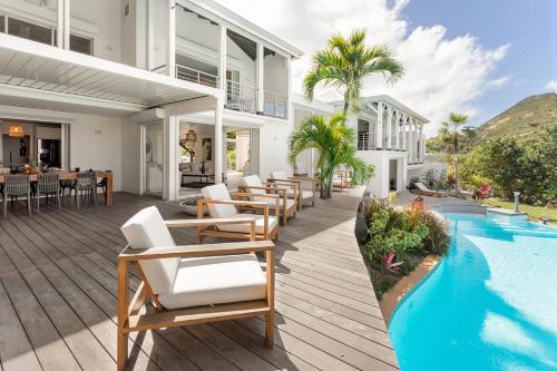 an outdoor deck with chairs and a swimming pool at 7 bedrooms Villa, Nestled in the heights of Anse Marcel, one of the most discreet bays of the island. in Saint Martin