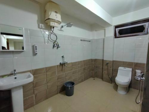 y baño con aseo blanco y lavamanos. en Gyatso Guest House en Tawang