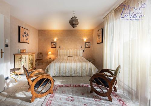- une chambre avec un lit et deux chaises dans l'établissement La Villa By Mama C-Gîte-Piscine-SPA, à Fontenay