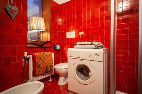 bagno piastrellato rosso con servizi igienici e lavatrice. di Modest & Cheap Tavern for a Spartan Retreat a Courmayeur
