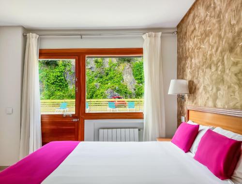 Schlafzimmer mit einem Bett mit rosa Kissen und einem Fenster in der Unterkunft Hotel Los Arces in Isla