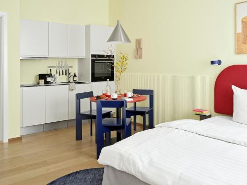 a room with a bed and a table with chairs and a kitchen at BRIK Apartment Hotel in Copenhagen