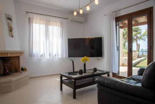 a living room with a couch and a tv at Agnanti Marina villa with private pool in Skouloúfia