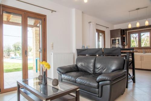 a living room with a leather couch and a table at Agnanti Marina villa with private pool in Skouloúfia