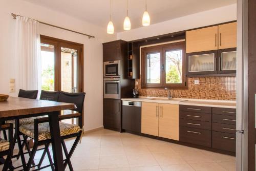 a kitchen with wooden cabinets and a table with a dining room at Agnanti Marina villa with private pool in Skouloúfia